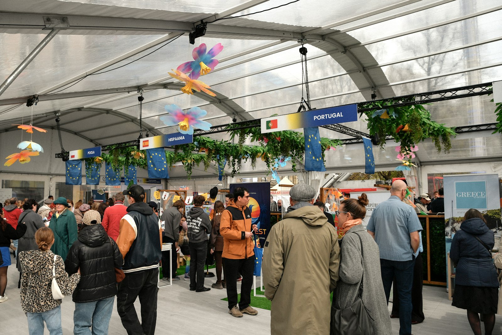 Crowd gathered inside a large tent with decorated stalls