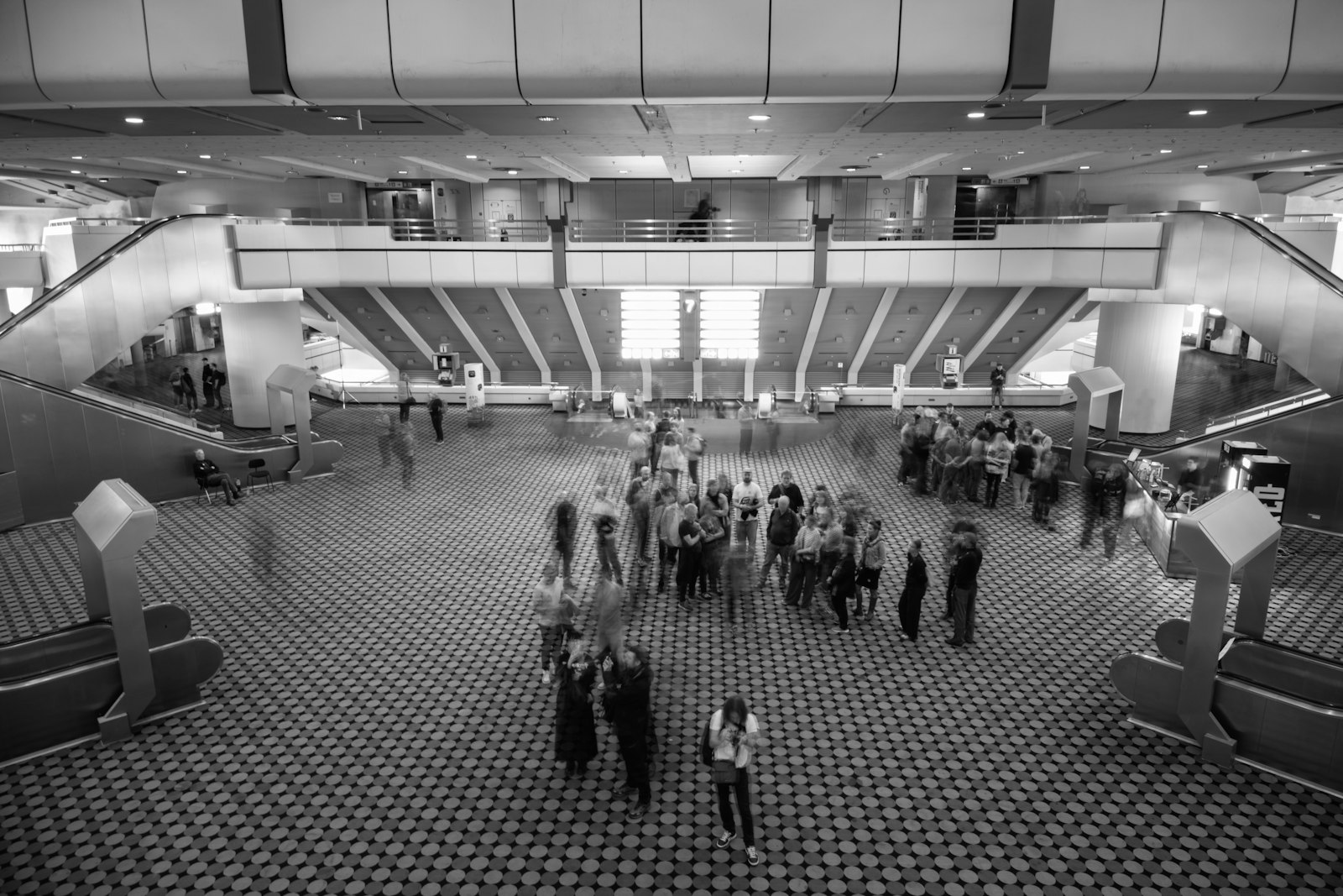 People gathered in a large, modern atrium with escalators